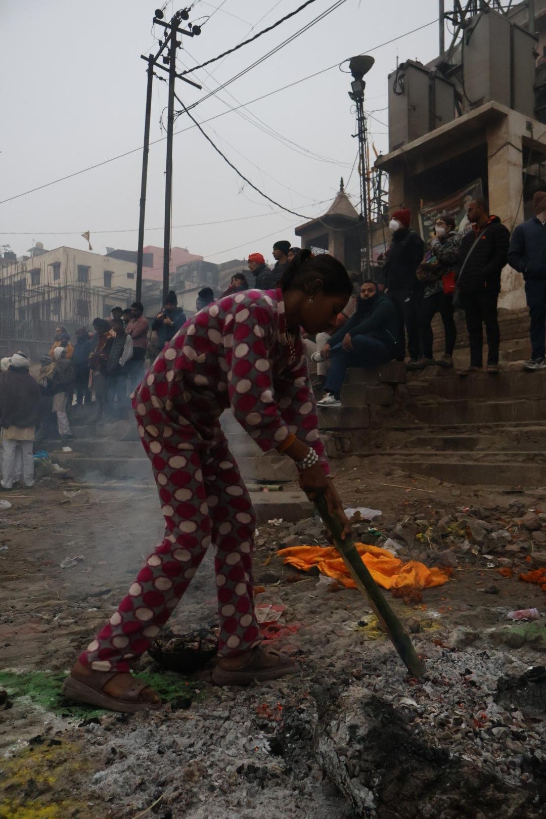Woman gathering warm embers at Harishchandra Ghat